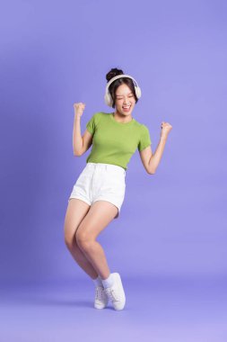 Pembe arka planda poz veren güzel Asyalı kızın tüm vücudu.