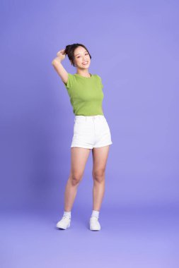 Pembe arka planda poz veren güzel Asyalı kızın tüm vücudu.