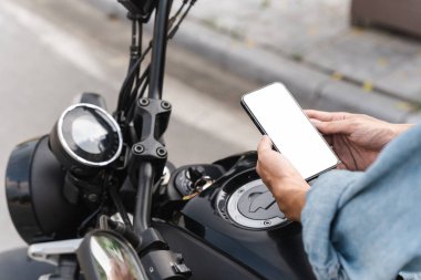 Moto 'nun üzerinde cep telefonu kullanan Asyalı adamın görüntüsü.