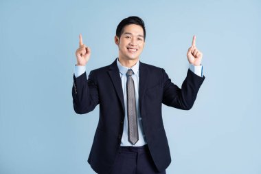 Asyalı işadamı portresi mavi arka planda takım elbise giyiyor