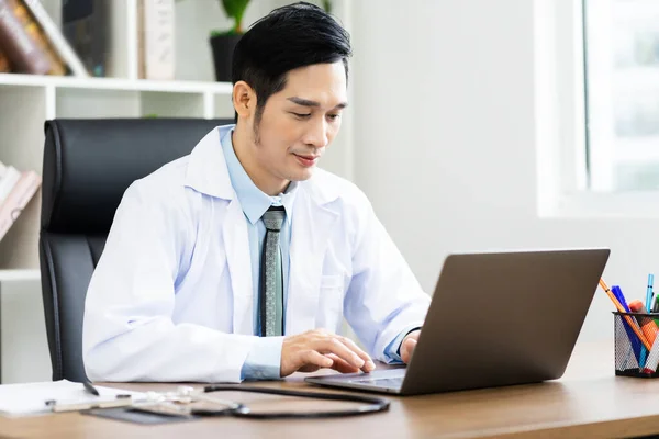 Asian male doctor portrait sitting at work