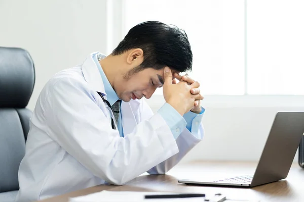 Asian male doctor portrait sitting at work