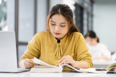 Üniversite kütüphanesinde okuyan Asyalı kız öğrencinin portresi