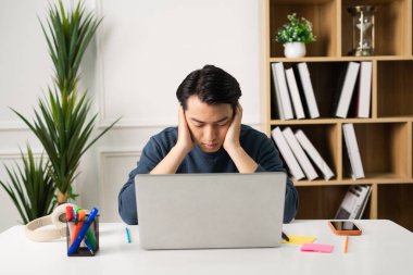 Asyalı bir adamın evde oturup çalışırken görüntüsü