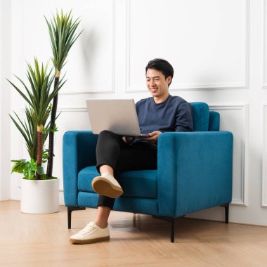 Evdeki kanepede oturan Asyalı adamın portresi.