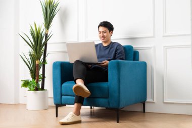 Evdeki kanepede oturan Asyalı adamın portresi.