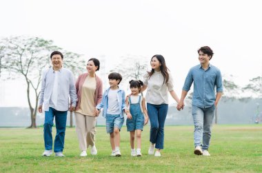 Parkta birlikte yürüyen Asyalı aile fotoğrafı.