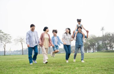 Parkta birlikte yürüyen Asyalı aile fotoğrafı.