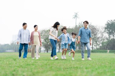 Parkta birlikte yürüyen Asyalı aile fotoğrafı.