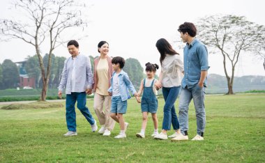 Parkta birlikte yürüyen Asyalı aile fotoğrafı.