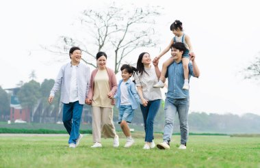 Parkta birlikte yürüyen Asyalı aile fotoğrafı.