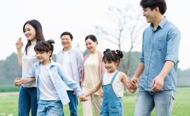 Parkta birlikte yürüyen Asyalı aile fotoğrafı.