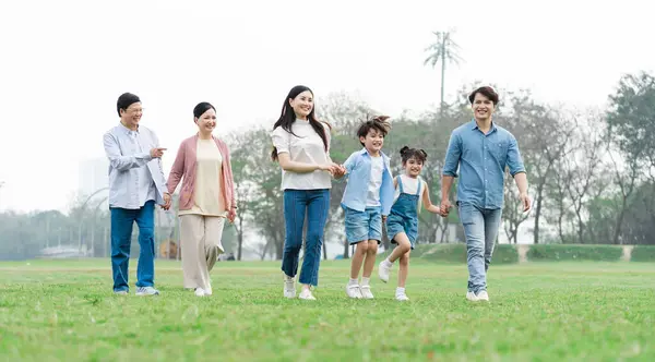 Parkta birlikte yürüyen Asyalı aile fotoğrafı.