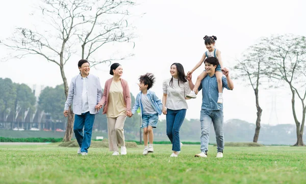 Parkta birlikte yürüyen Asyalı aile fotoğrafı.