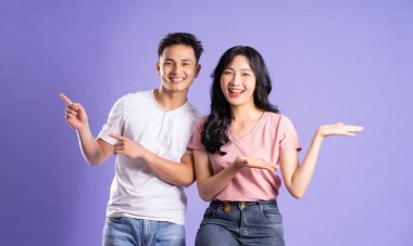 Mor arkaplanda poz veren Asyalı çift görüntüsü