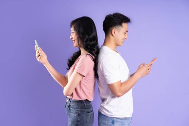 Asyalı bir çiftin elinde akıllı telefon resmi, mor arka planda izole edilmiş.