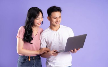 Mor arka planda izole edilmiş, dizüstü bilgisayar kullanan Asyalı bir çift görüntüsü