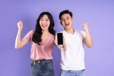 Asyalı bir çiftin elinde akıllı telefon resmi, mor arka planda izole edilmiş.