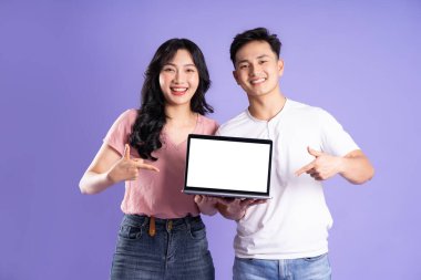 Mor arka planda izole edilmiş, dizüstü bilgisayar kullanan Asyalı bir çift görüntüsü