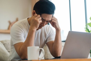 Evdeki kanepede oturan Asyalı adamın portresi.