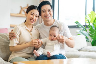 Gülümseyen anne ve baba yeni doğan oğlunu kucağında tutuyor.