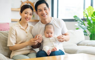 Gülümseyen anne ve baba yeni doğan oğlunu kucağında tutuyor.