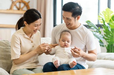 Gülümseyen anne ve baba yeni doğan oğlunu kucağında tutuyor.