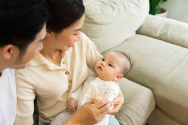 Gülümseyen anne ve baba yeni doğan oğlunu kucağında tutuyor.