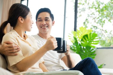 Asyalı bir çiftin evdeki koltukta oturduğu görüntüsü.