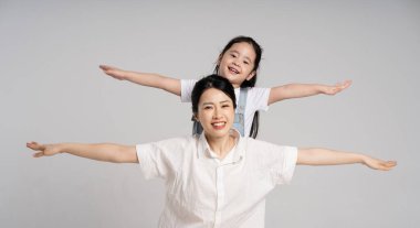 Beyaz arka planda poz veren Asyalı bir anne ve kızın portresi.