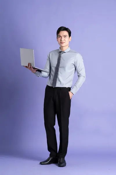 Portrait of Asian male businessman standing and posing on purple background