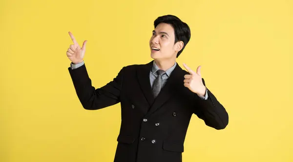 Portrait of Asian male businessman. wearing a suit and posing on a yellow background