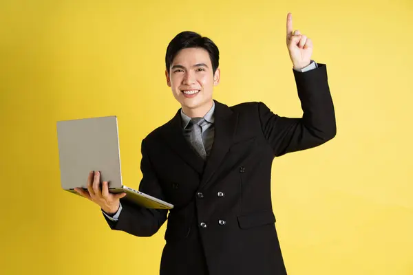 Portrait of Asian male businessman. wearing a suit and posing on a yellow background