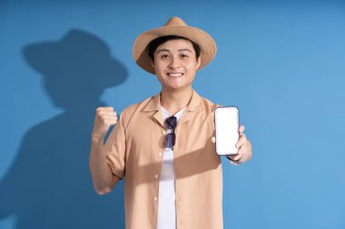 Mavi arka planda poz veren Asyalı bir adamın portresi, yazın seyahat ediyor.