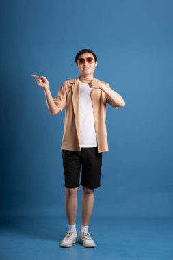 Mavi arka planda poz veren Asyalı bir adamın portresi, yazın seyahat ediyor.