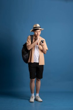 Mavi arka planda poz veren Asyalı bir adamın portresi, yazın seyahat ediyor.