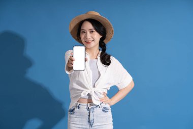 Mavi arka planda poz veren Asyalı bir kızın portresi. Yazın seyahat ediyor.