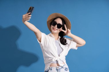 Mavi arka planda poz veren Asyalı bir kızın portresi. Yazın seyahat ediyor.