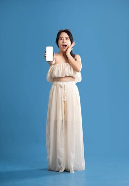 Mavi arka planda poz veren Asyalı bir kızın portresi. Yazın seyahat ediyor.