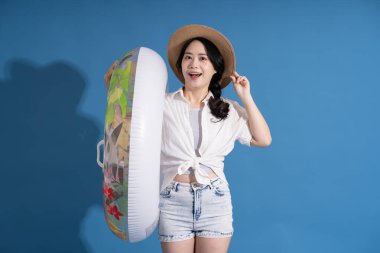 Mavi arka planda poz veren Asyalı bir kızın portresi. Yazın seyahat ediyor.