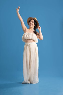 Mavi arka planda poz veren Asyalı bir kızın portresi. Yazın seyahat ediyor.