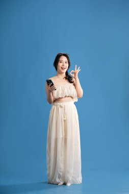 Mavi arka planda poz veren Asyalı bir kızın portresi. Yazın seyahat ediyor.