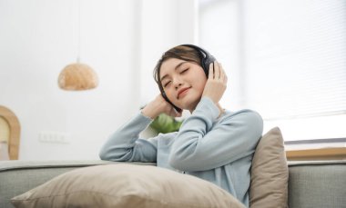 Evdeki kanepede oturan Asyalı kadının portresi.