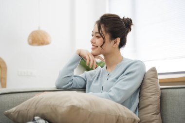 Evdeki kanepede oturan Asyalı kadının portresi.