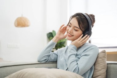 Evdeki kanepede oturan Asyalı kadının portresi.