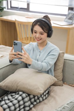 Evdeki kanepede oturan Asyalı kadının portresi.