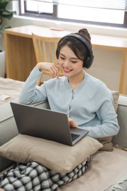 Evdeki kanepede oturan Asyalı kadının portresi.