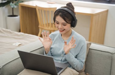 Evdeki kanepede oturan Asyalı kadının portresi.