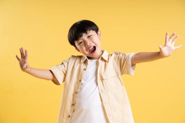 Sarı arka planda poz veren sevimli Asyalı çocuk portresi.