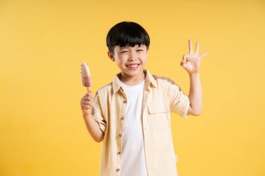 Sarı arka planda poz veren sevimli Asyalı çocuk portresi.